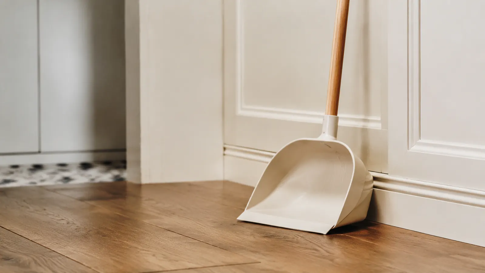A clear floor in a kitchen with a dustpan nearby, no scattered litter